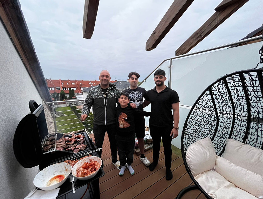 Dört genç erkek ve bir çocuk barbekü başında poz veriyor, baba henüz görselde yer almıyor