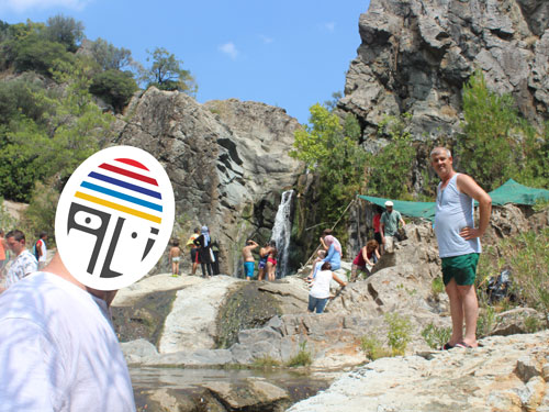 Şelale önünde çekilmiş, arka planda çok sayıda insan bulunan fotoğraf