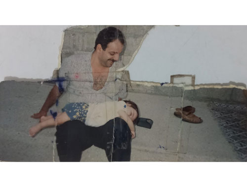 Yırtılmış, bantlanmış, mürekkep lekeleri bulunan ve parçaları eksik baba ile çocuk fotoğrafı